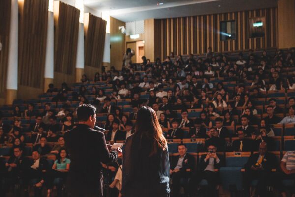 Woman and Man speaking before crowd in a conference room